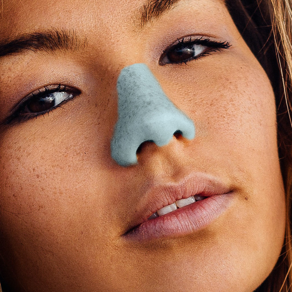 Neon blue NOZ sunscreen on woman’s nose